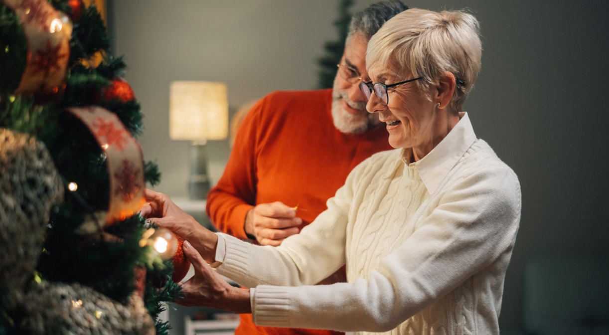 Älteres Paar schmückt zu Hause den Weihnachtsbaum